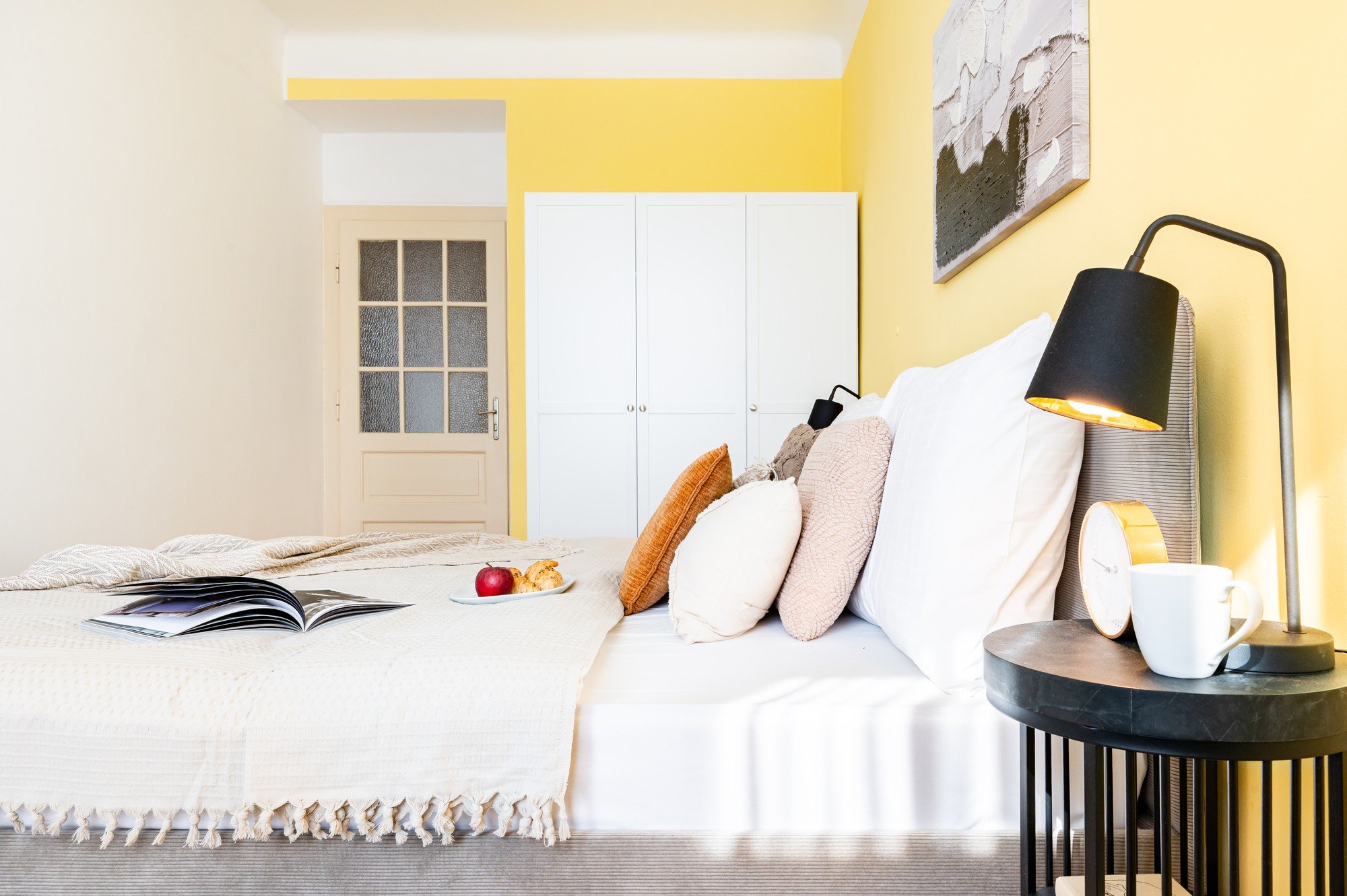 Prostor sedaj deluje sveže, optimistično in usklajeno, s toplim rumenim poudarkom, plastenjem tekstilij ter detajli, ki spalnico spreminjajo v prijeten, a hkrati sodoben kotiček za počitek.